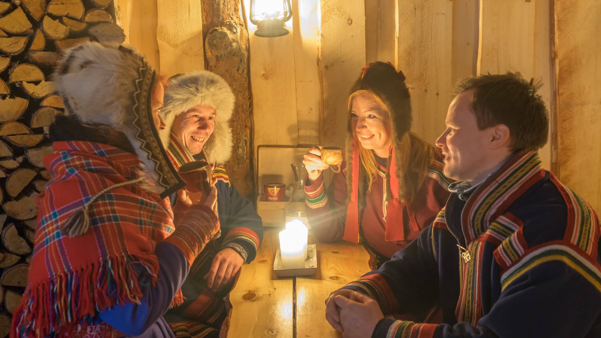 Guests sharing hot drinks by lantern light inside the gamme